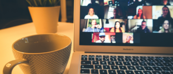 Ordinateur avec une visioconférence Zoom, posé sur une table avec une tasse de café et une plante