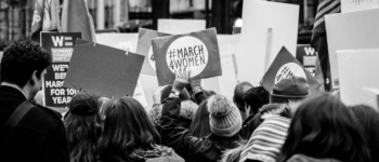 photo d'une manifestation pour les droits des femmes en angleterre avec une foule et des pancartes