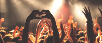 Photo d'un concert avec des mains en l'air qui forment un coeur