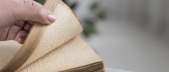 Une main ouvre un livre en braille