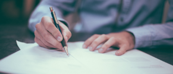 Personne en train de remplir des papiers avec un stylo sur une table