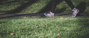 photo de jambes d'une personne qui marche dans l'herbe avec un jogging des baskets