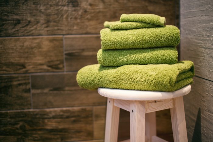 Serviettes de bains vertes pliées et posées sur un tabouret