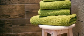 Serviettes de bains vertes pliées et posées sur un tabouret