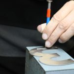 ouvrier ajoutant des billes de braille à un panneau signalétique