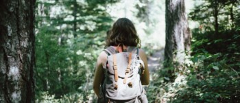 Personne de dos portant un sac à dos marchant dans une forêt