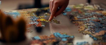 Main qui assemble des pièces d'un puzzle sur une table en verre transparente